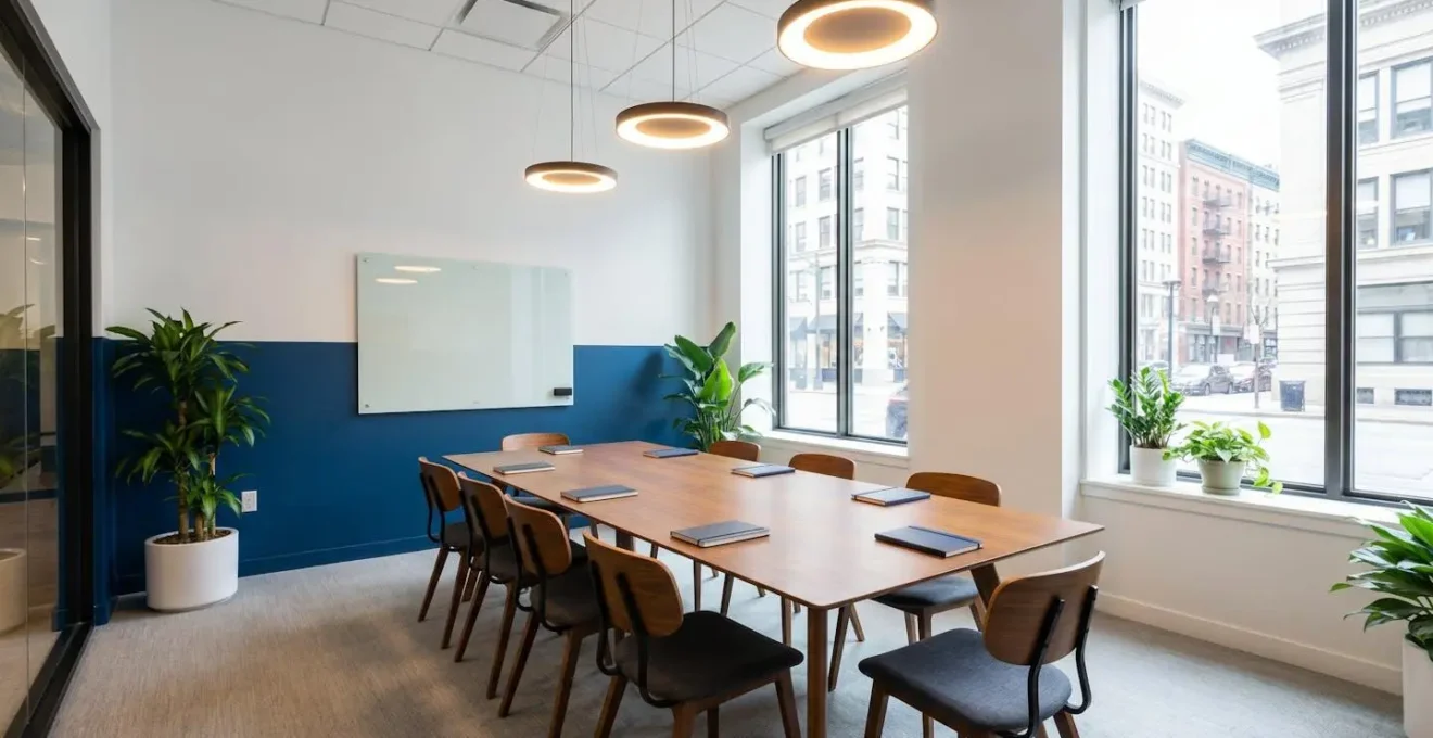 Salle de conférence rénovée avec peinture bicolore, éclairage LED et plantes vertes, ambiance professionnelle et lumineuse
